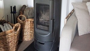 Ein modernes Wohnzimmer mit Kaminofen, Korbwäsche und einer Couch.