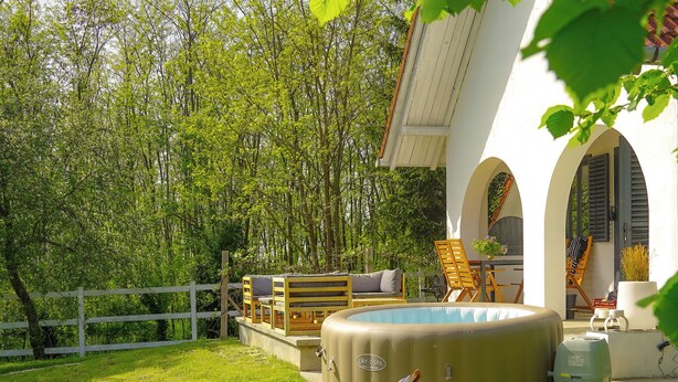 Ein Garten mit Schwimmbad, Liegestühlen und einem weißen Gebäude mit Bögen.