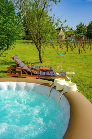 Un jacuzzi al aire libre con dos sillones reclinables y dos copas de vino blanco.
