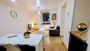 En moderne stue med spisebord, stole, sofa, fjernsyn og en globus på en hylde.