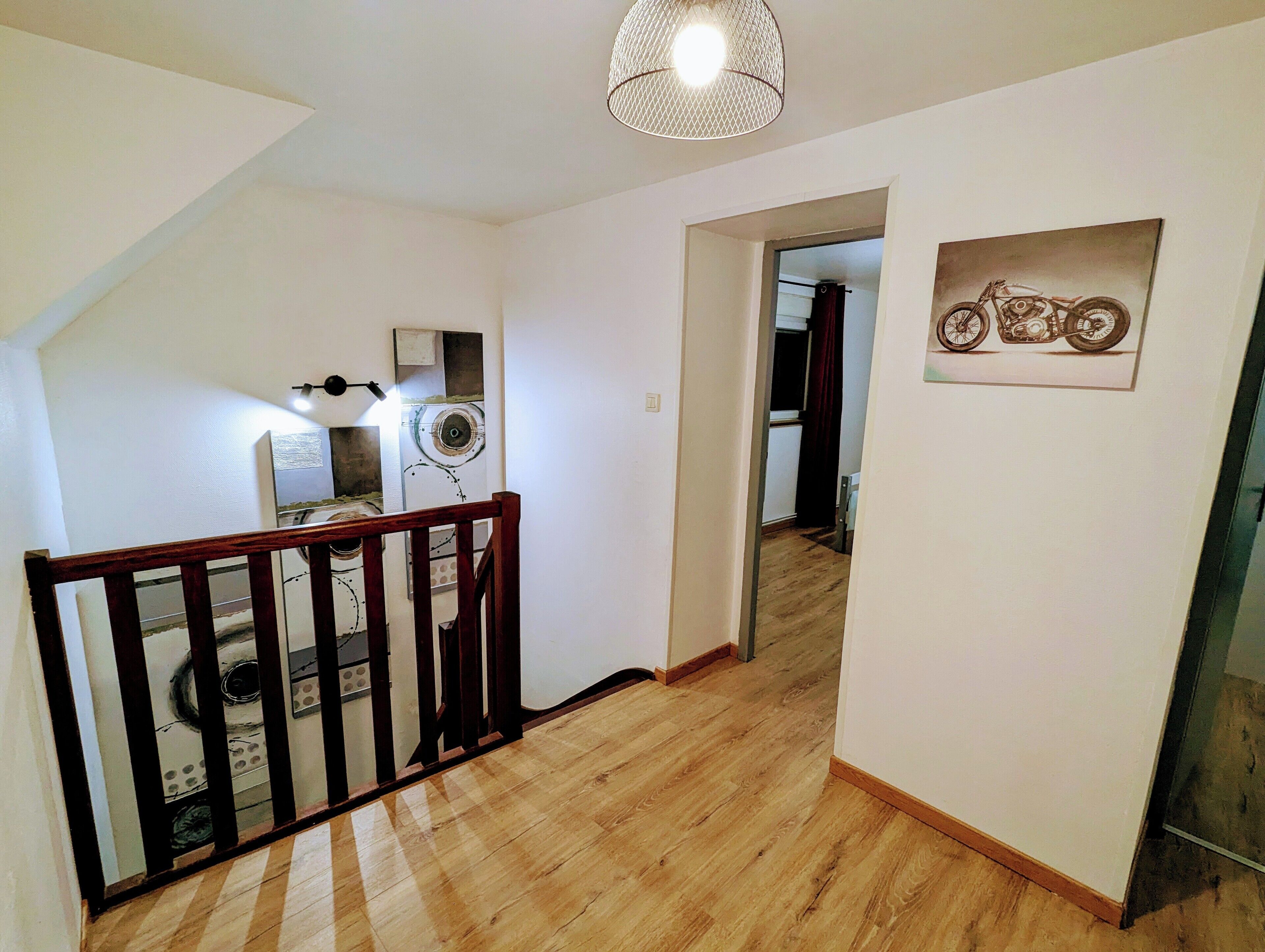 Una escalera con barandillas de madera que conduce a una plataforma. Se observa un candelabro en el techo.