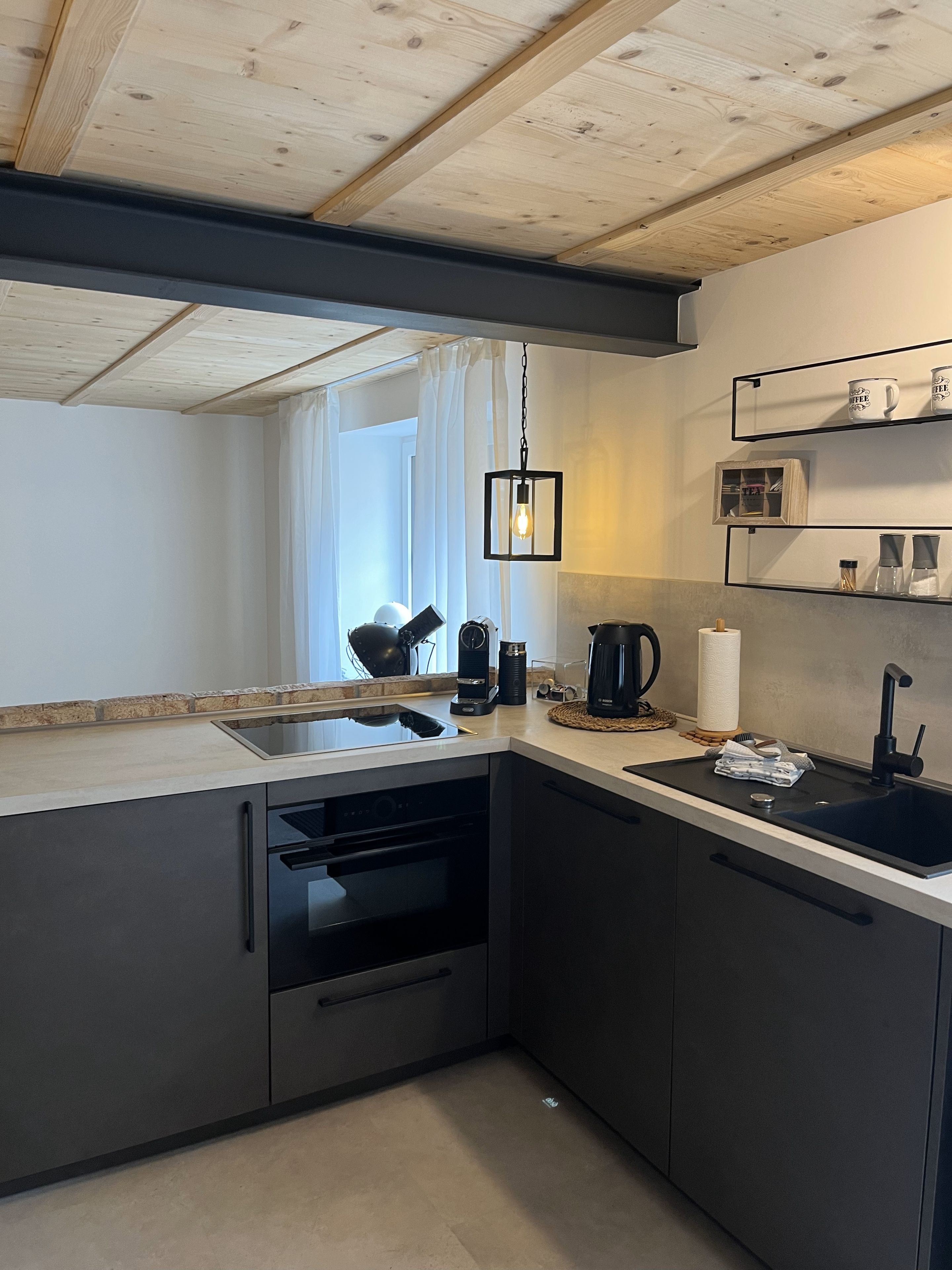 Cozinha moderna com forno embutido, cafeteira e pia.