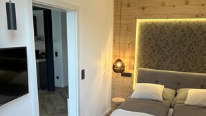 A bedroom with a bed, a TV mounted on the wall, a desk, and a chair. - Wyzenborne (Sontra)