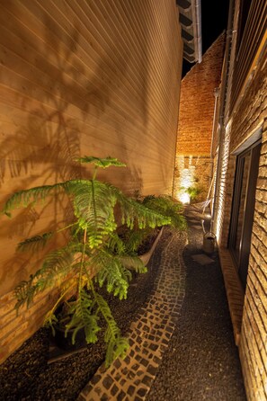 Un vialetto stretto delimitato da muri in mattoni, che conduce all'ingresso di un edificio.