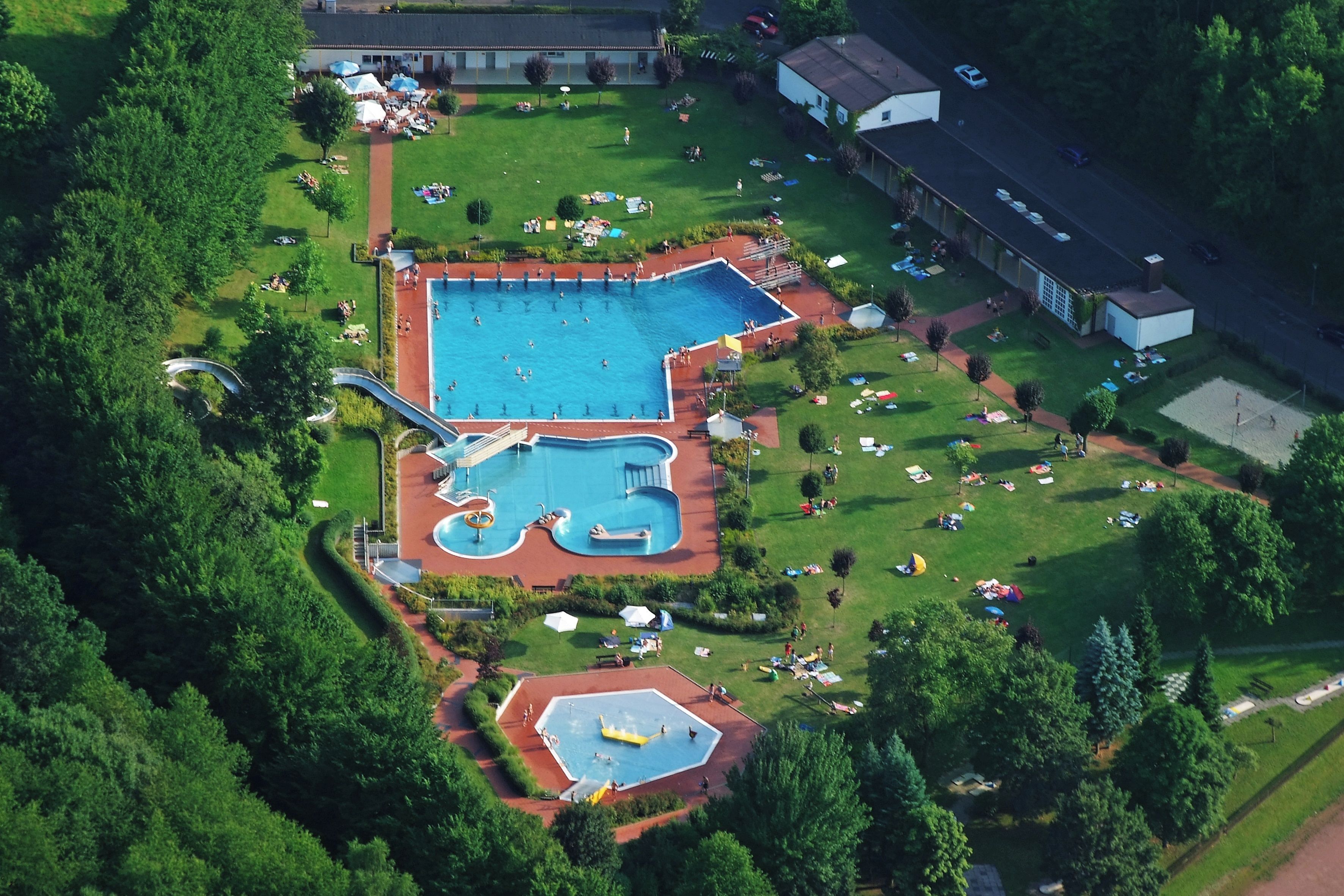 Vista aérea de un complejo de piscinas con varias albercas y un tobogán de agua.