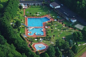 Vista aerea di un complesso piscine con diverse vasche e uno scivolo acquatico.