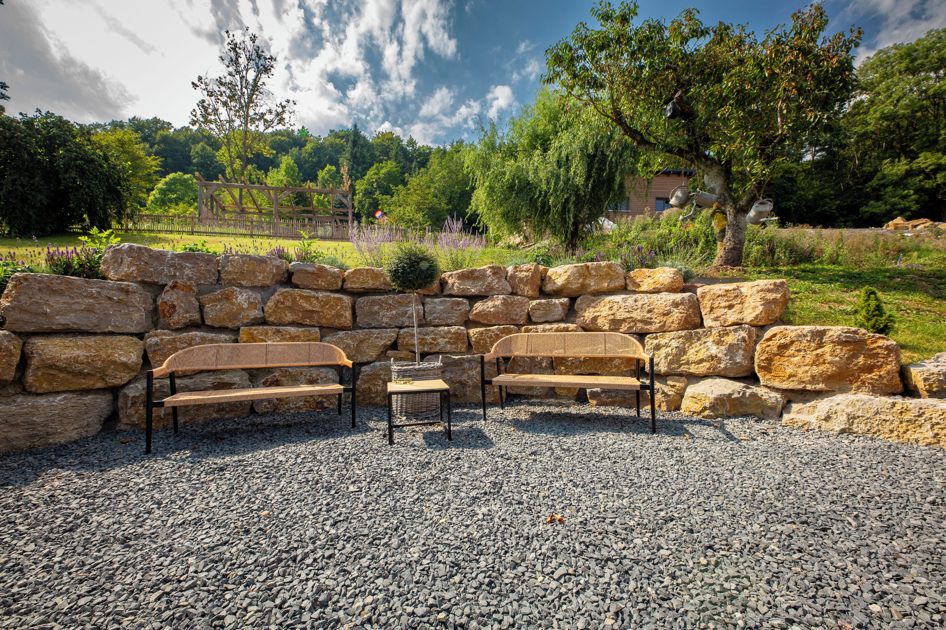 A stone wall with a seating area consisting of two benches and a table.
