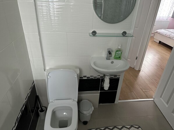 Een badkamer met toilet, wastafel en spiegel.