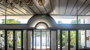 Eine geräumige Lobby mit Blick auf ein Gewässer, einer Decke mit runden Leuchten und einem Schild, das einen Ausgang weist.