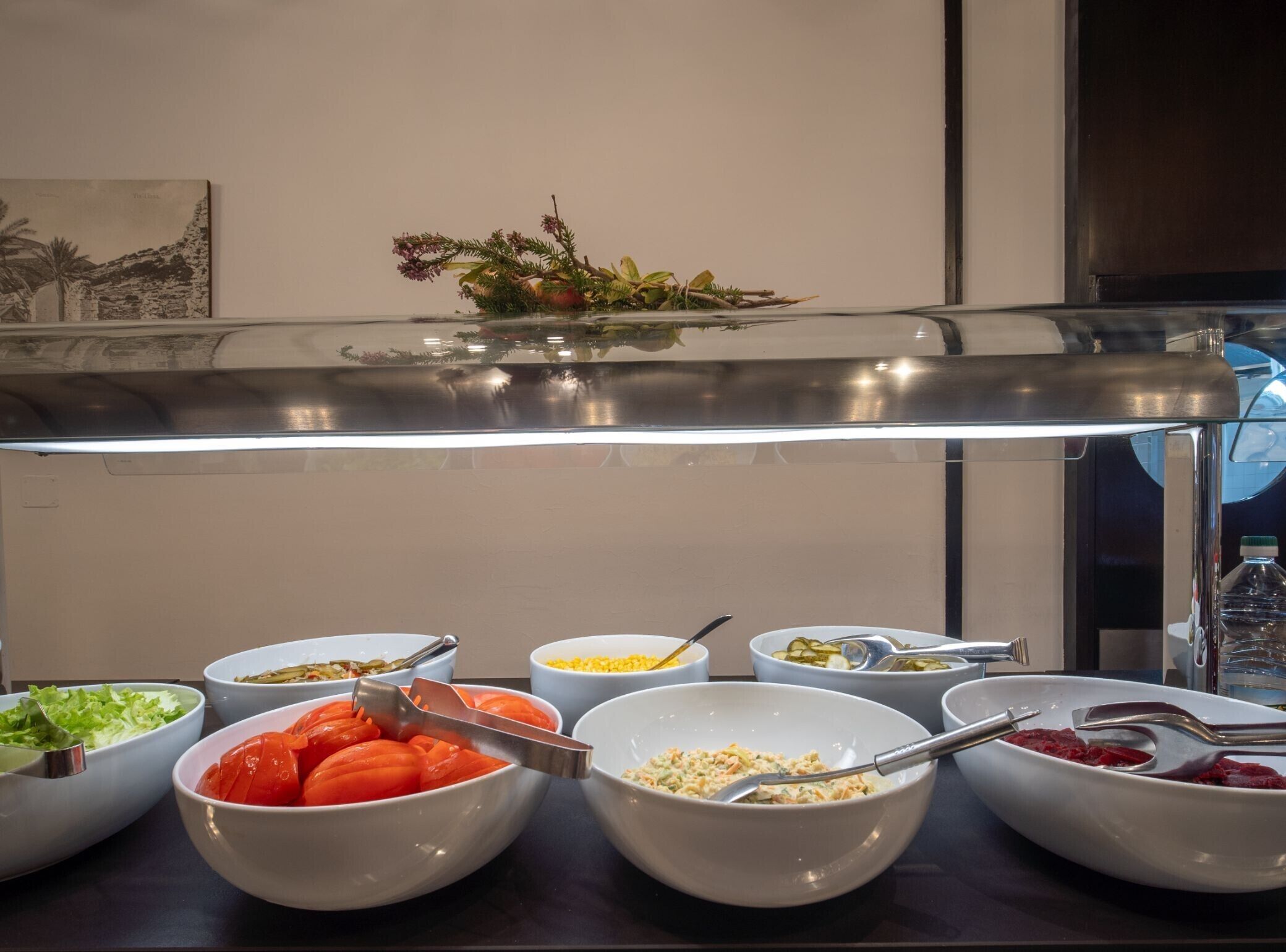 A buffet with various food items including salads, fruits, and a decorative centerpiece.