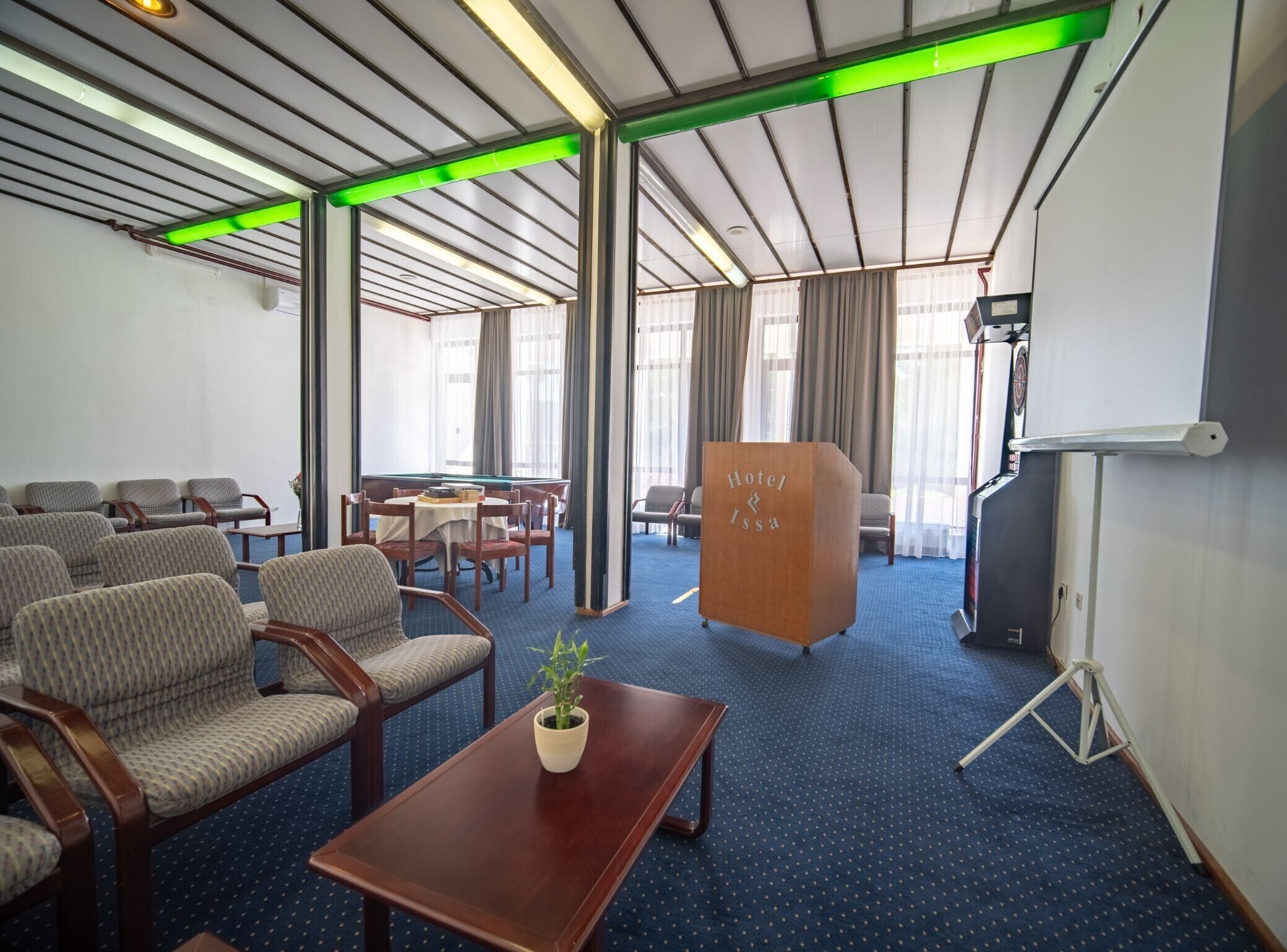 Une chambre d’hôtel avec un tapis bleu, des meubles en bois, un pupitre en bois et un écran de projection.