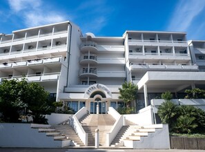 A multi-story hotel with a central entrance, balconies on each floor, and a staircase leading to the entrance. - Hotel Issa - Double Room Sea View 13 (Vis)