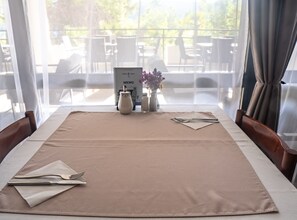 A neatly set dining table with a menu, salt and pepper shakers, and a vase of flowers. - Hotel Issa - Double Room Sea View 13 (Vis)