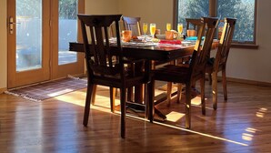 A dining area with a wooden table and chairs, a chandelier, and a view through large windows. - Quiet Retreat w/ Jacuzzi Tub and Fire Pit in Beautiful Prescott! (Prescott)