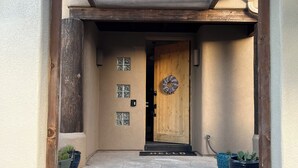 A stone-paved entrance with a wooden door, potted cacti, and a 'HELLO' mat. - Quiet Retreat w/ Jacuzzi Tub and Fire Pit in Beautiful Prescott! (Prescott)
