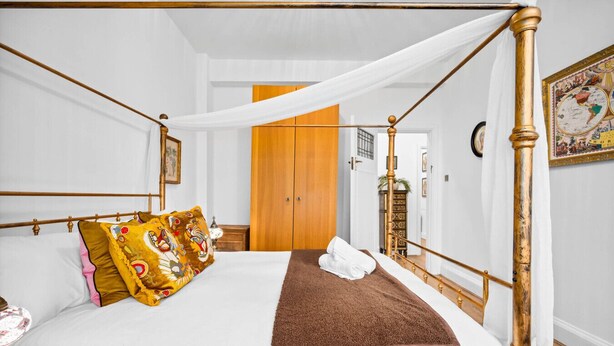 Ein Bett mit Baldachin, ein Holzschrank und eine gerahmte Karte an der Wand.