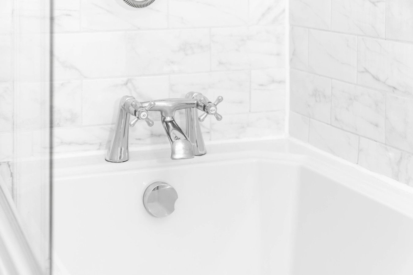 Ein Badezimmer mit einer weißen Badewanne, einem Chrom-Wasserhahn und einem Abfluss.