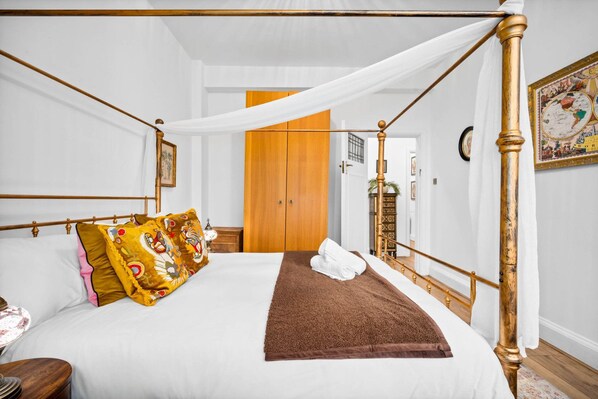Una cama con dosel, un armario de madera y un mapa enmarcado en la pared.