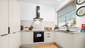 Eine moderne Küche mit weißen Schränken, einem schwarzen Backofen und einem Fenster mit Jalousien.