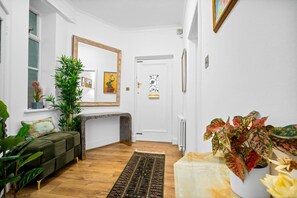 Una sala de estar con sofá, banca, chimenea y diversas plantas.