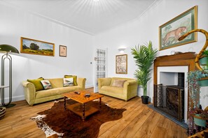 Ein Wohnzimmer mit zwei Sofas, einem Couchtisch, einem Kamin und einer großen Küstenpflanze.