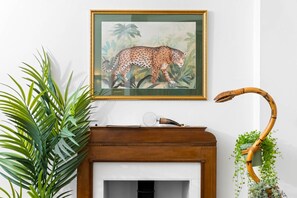 A framed painting of a leopard on a wall, a fireplace with a decorative item, and a plant with a curved bamboo structure. - Stylish Two Bedroom Apartment - 2 Parking Spaces - Balcony (Birmingham)