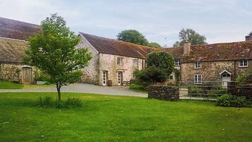 A stone building with a grassy lawn and a tree in front.