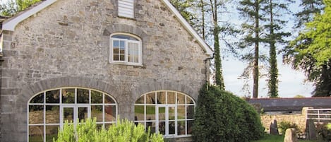 A stone building with two arched windows and a small dormer window.