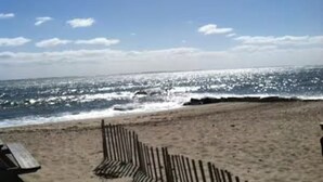 Una playa con una valla de madera y una vista despejada del océano.