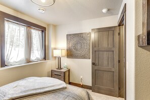 Ein Schlafzimmer mit einem Bett, einem Nachttisch mit Lampe, einem Wandbild und einer Tür.