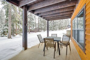 Überdachte Terrasse mit Tisch und Stühlen mit Blick auf einen verschneiten Wald.