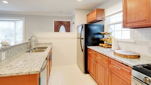 Una cocina moderna con encimeras de granito, electrodomésticos de acero inoxidable y armarios de madera.
