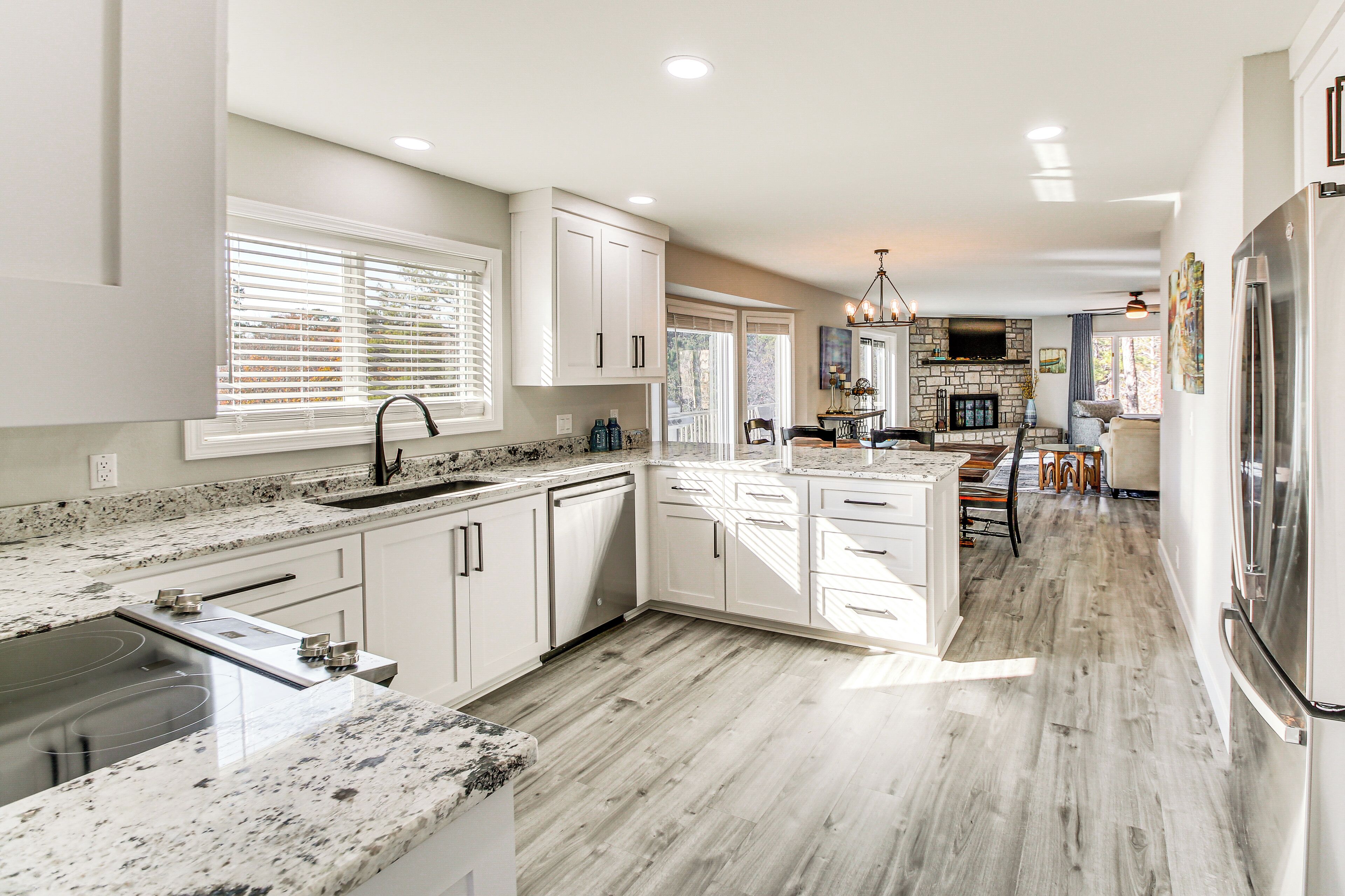 A modern kitchen with white cabinets, granite countertops, and a large island.