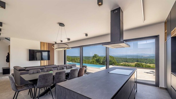 Una cocina moderna con una isla grande, un comedor y un televisor montado en la pared.