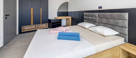 A modern bedroom with a bed, a wardrobe, a desk, and an air conditioning unit.