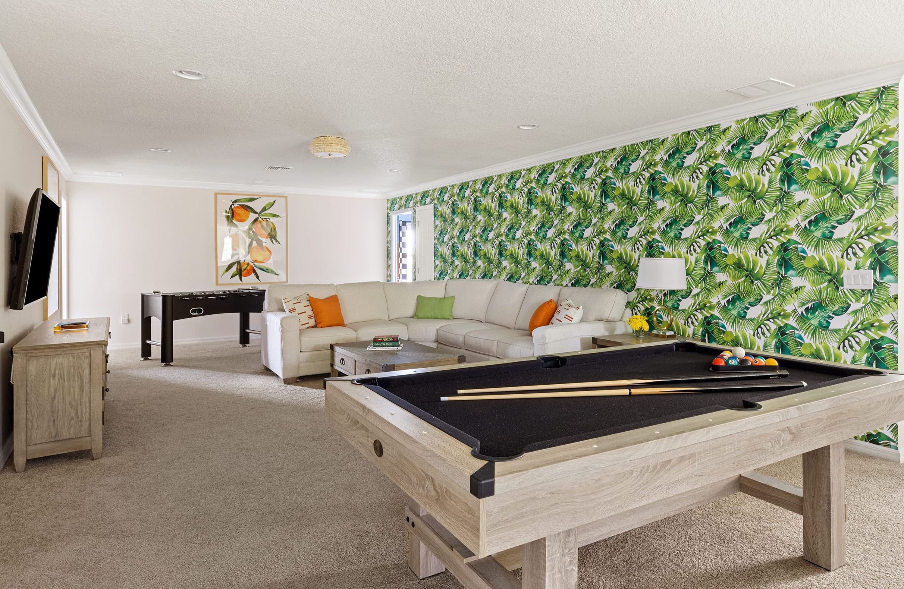 A living room with a pool table, a sofa, a coffee table, and a television.