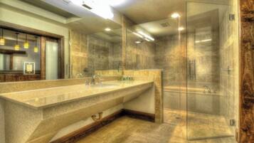 A modern bathroom with a large vanity, a glass shower enclosure, and a wooden accent wall.