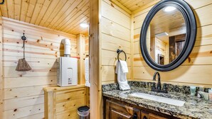 A wooden cabin bathroom with a granite countertop sink, a mirror, and a towel rack.