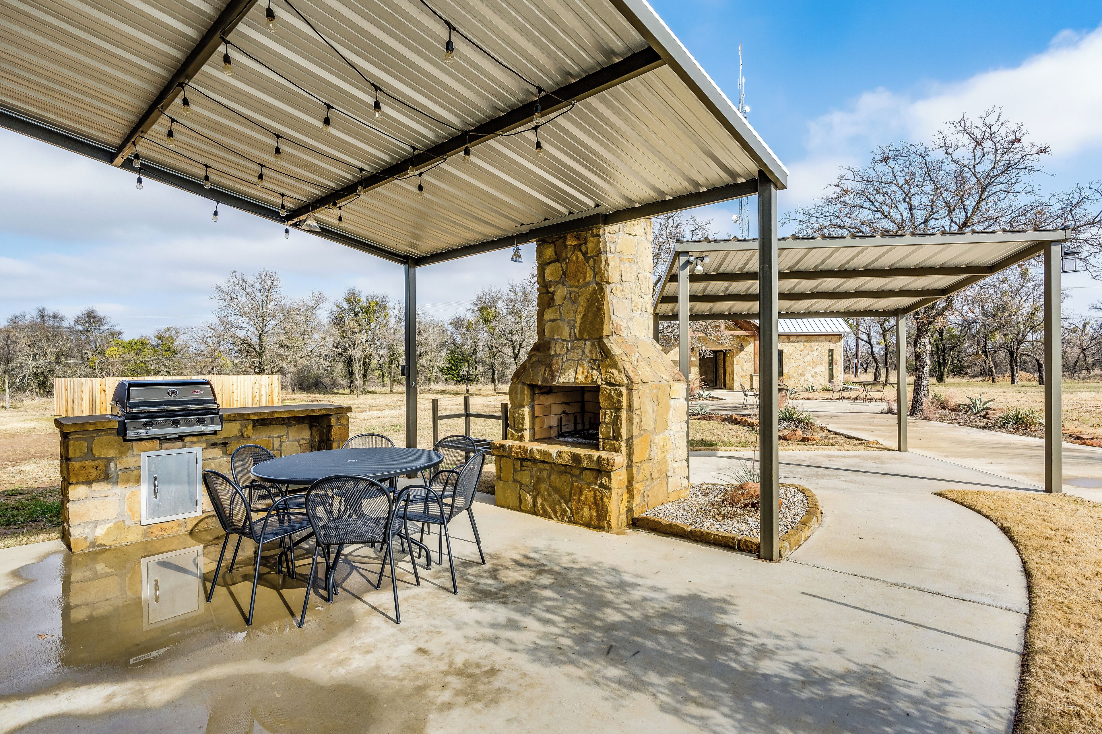 An outdoor patio with a stone fireplace, grill, and seating area.
