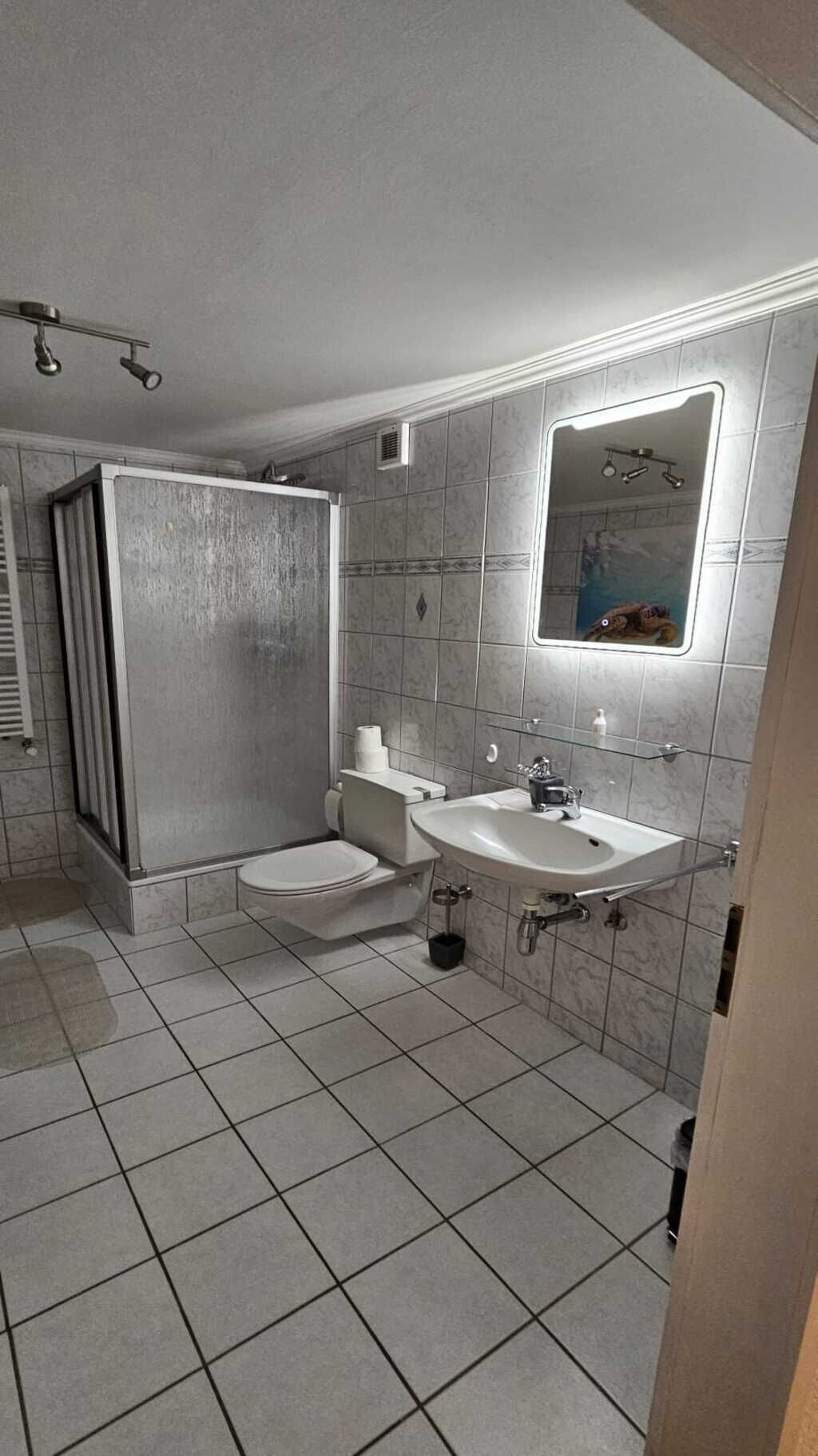 Ein modernes Badezimmer mit bodenebenen Dusche, Toilette und Waschbecken.
