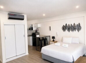 Habitación de hotel con cama, escritorio, microondas y armario.