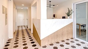 Un espace d’accueil moderne avec un comptoir en marbre, un revêtement de sol aux motifs géométriques et un grand miroir.