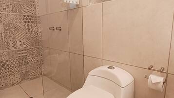 A modern bathroom with a toilet, a glass shower enclosure, and a patterned wall.