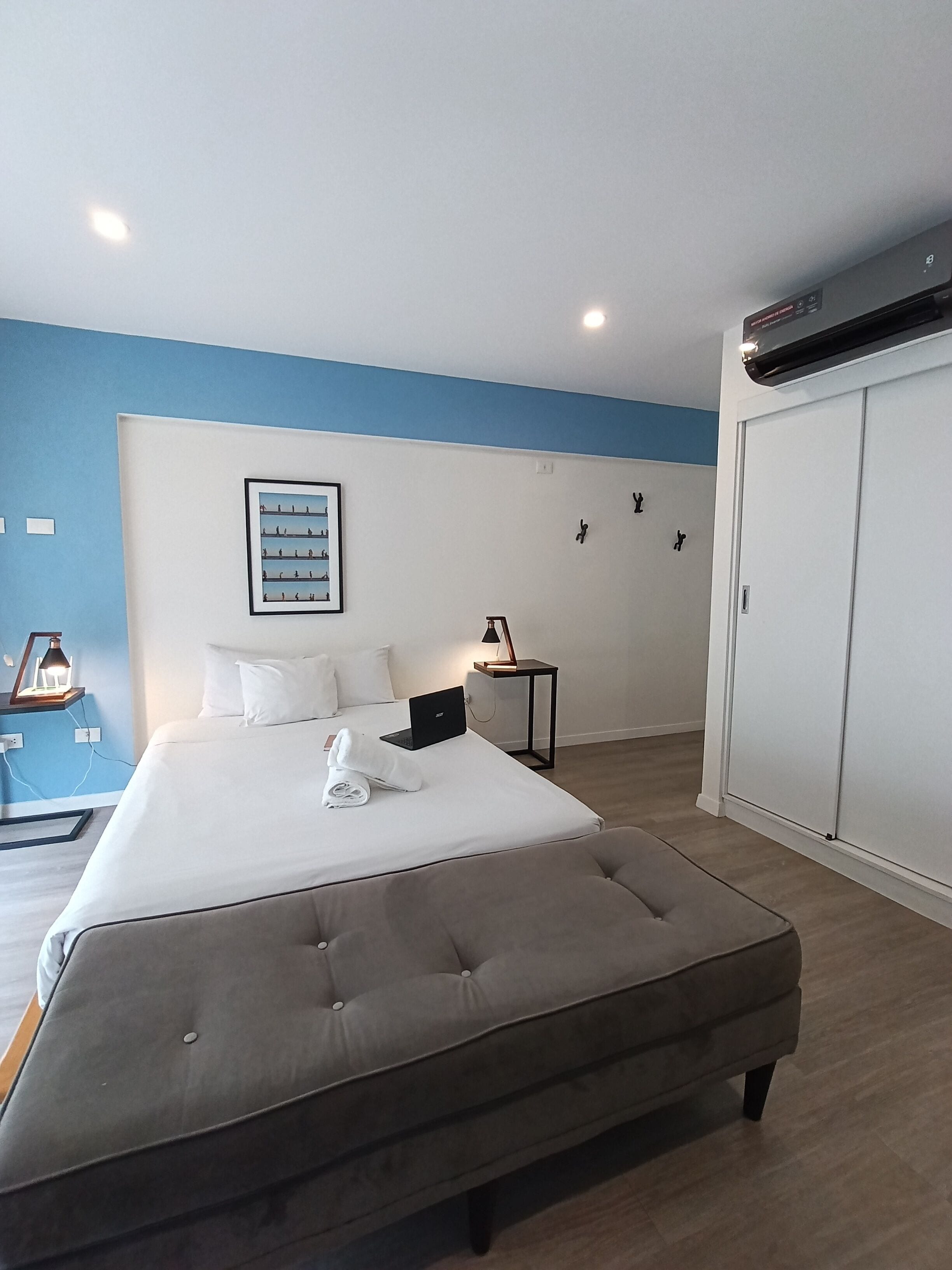 Hotelkamer met een groot bed, een bureau, een stoel, een kledingkast en een wandairconditioner.