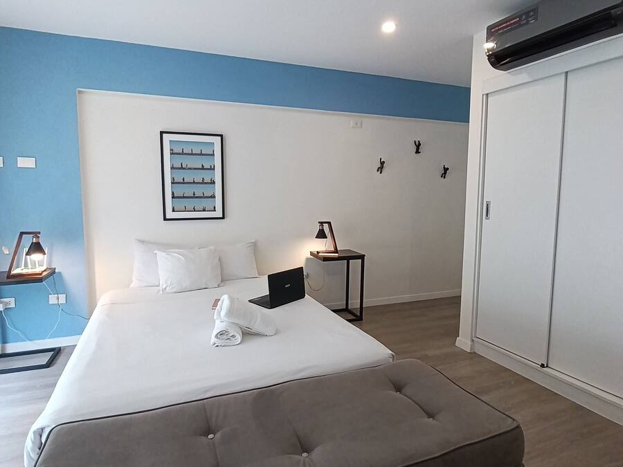 Hotelkamer met een groot bed, een bureau, een stoel, een kledingkast en een wandairconditioner.