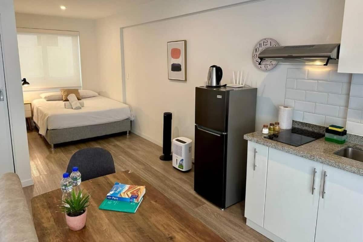 A compact hotel room with a bed, kitchenette, and a small dining area.
