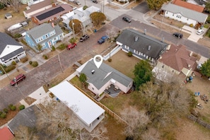 An aerial view of a residential area with houses, a paved road, and a marked location.