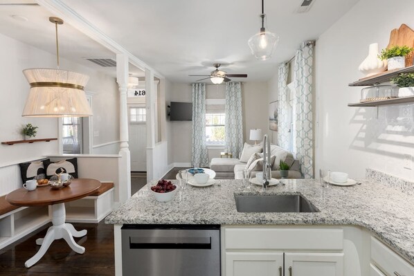 A modern kitchen with a granite countertop, stainless steel appliances, and a dining area with a wooden table and chairs.