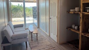 Una habitación con un sofá gris, una mesita pequeña y un mueble de madera con estantes.