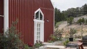 Un granero rojo con detalles blancos, mesas de picnic de madera al aire libre y barriles.